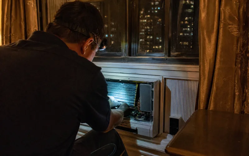 Technician performing emergency AC repair in a Fordham Bronx apartment